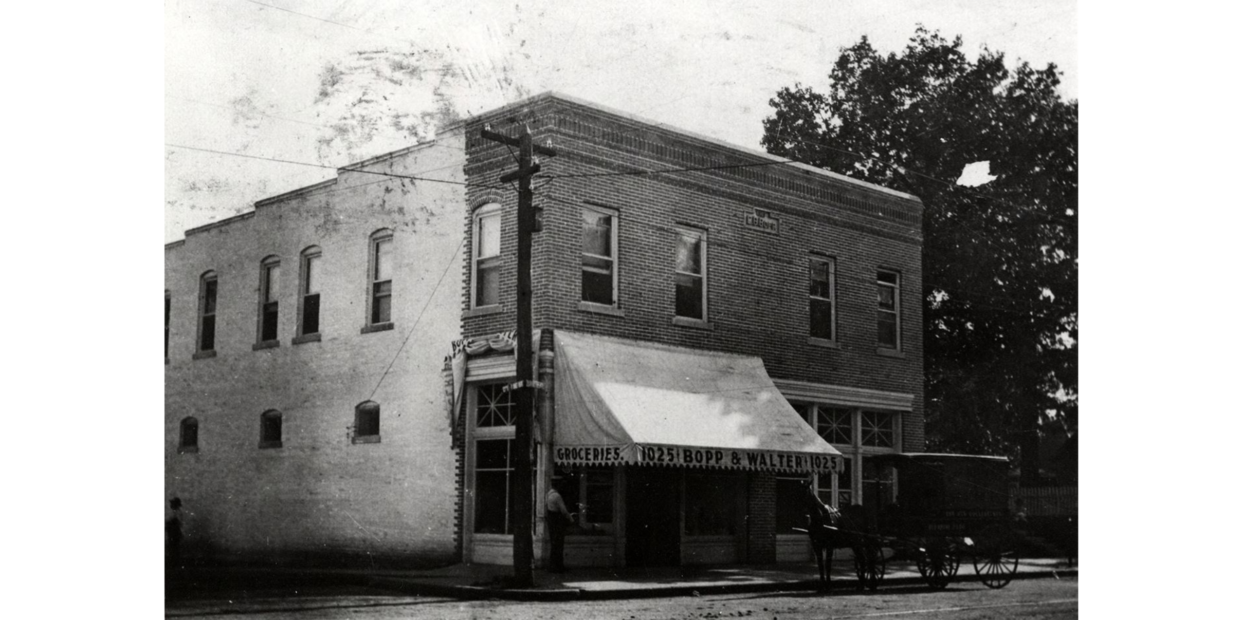 A two-story brick building. A horse-drawn buggy is parked in front of the building. The canopy over the entrance reads: "Groceries. 1025. Bopp & Walter. 1025."