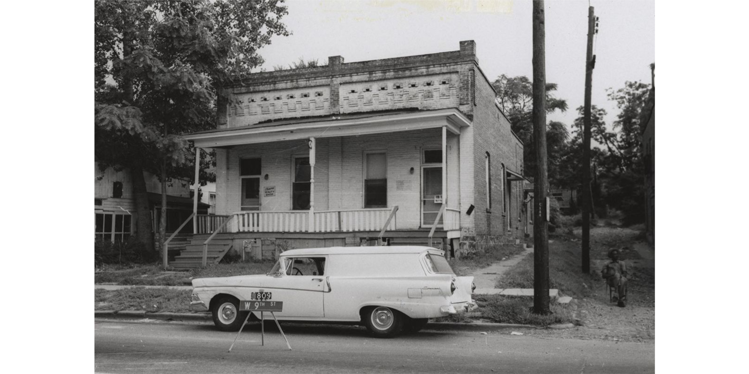 A brick duplex with a station wagon parked in front of the building. 