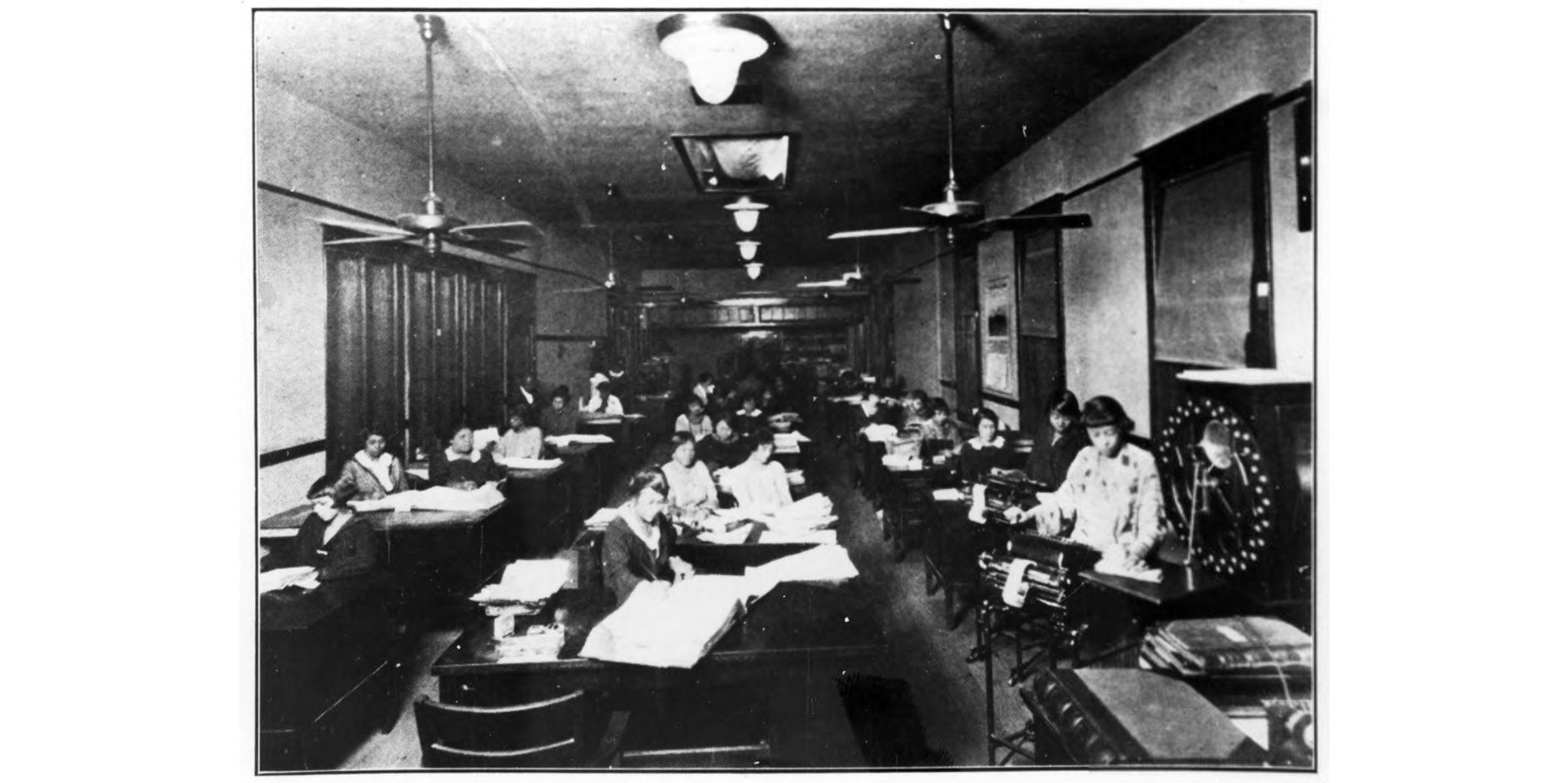 African American women working in an office space where desks are arranged in rows. The desks have both typewriters and papers on them.