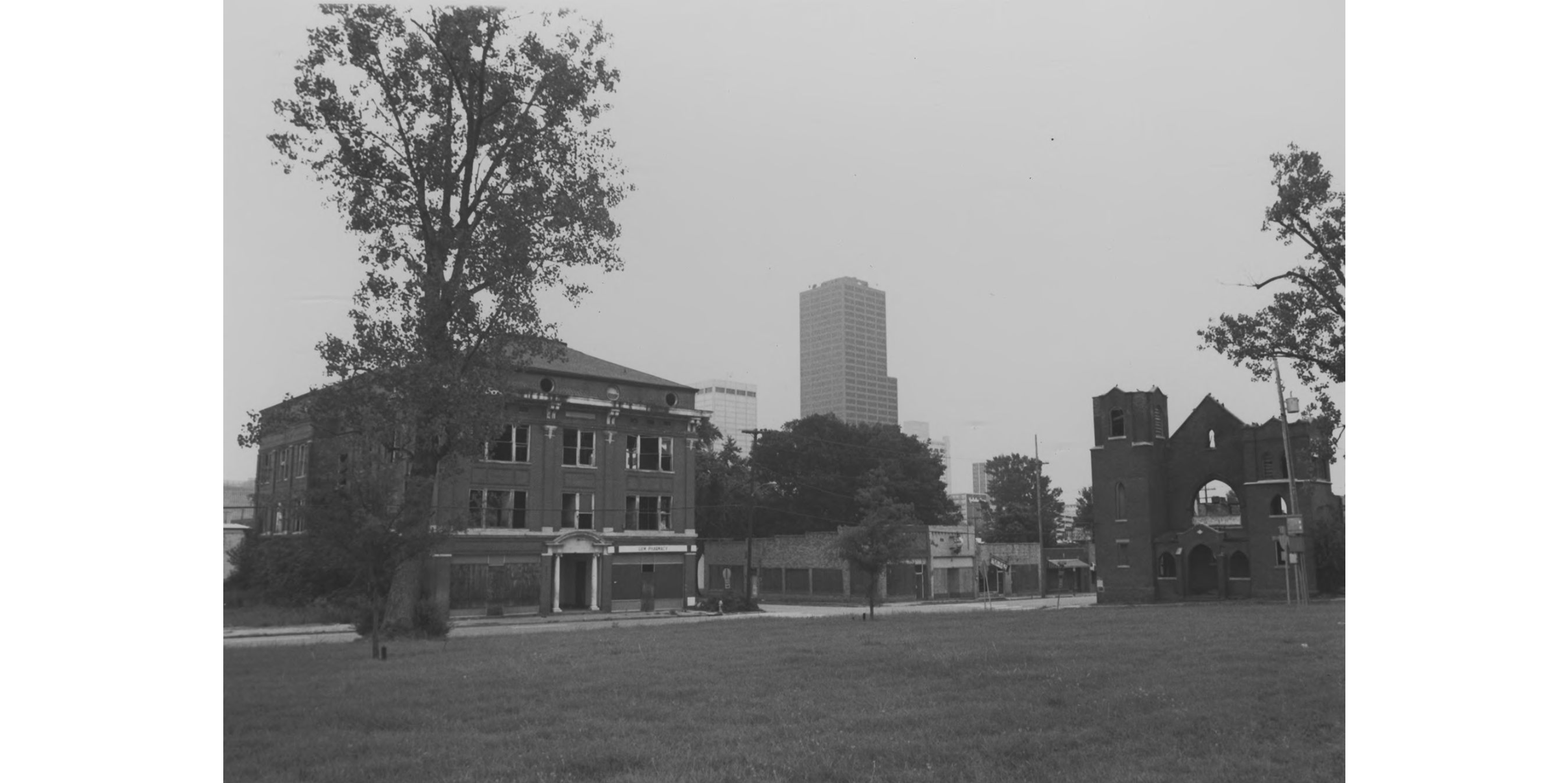 A skyline view with multiple brick buildings in the foreground and tall tower buildings in the distance.