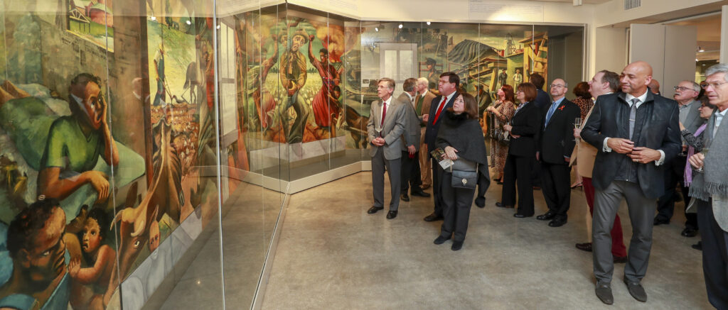 A group of people gathered to view a mural on display. 