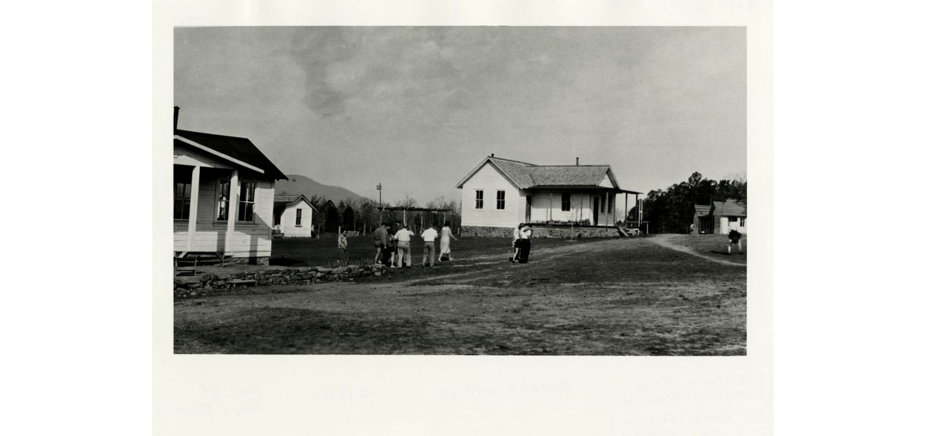 A group of people walking on a dirt path towards a building in the background.